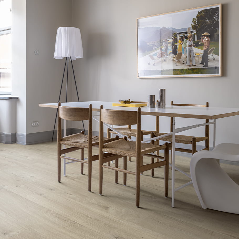 harmaa vinyylilattia ruokasalissa, jossa on harmaat seinät ja puinen pöytä